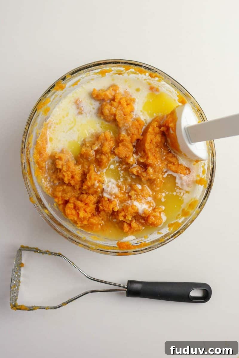 Sweet Potato Casserole Made with Canned Yams — Quick Holiday Side 6 Creamy sweet potato casserole filling mixed with eggs, butter, and cinnamon in a bowl with an immersion blender- Hostess At Heart
