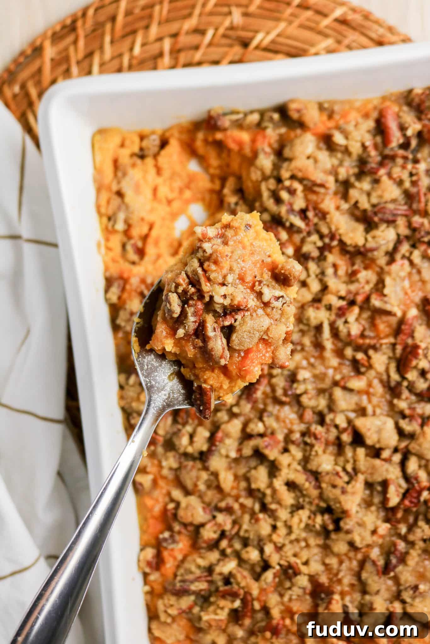 Sweet Potato Casserole Made with Canned Yams — Quick Holiday Side 10 Close-up of a spoon with a serving of sweet potato casserole made from canned yams and topped with a crusty pecan layer - Hostess At Heart