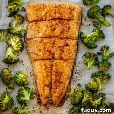 Large salmon fillet and roasted broccoli on a sheet pan