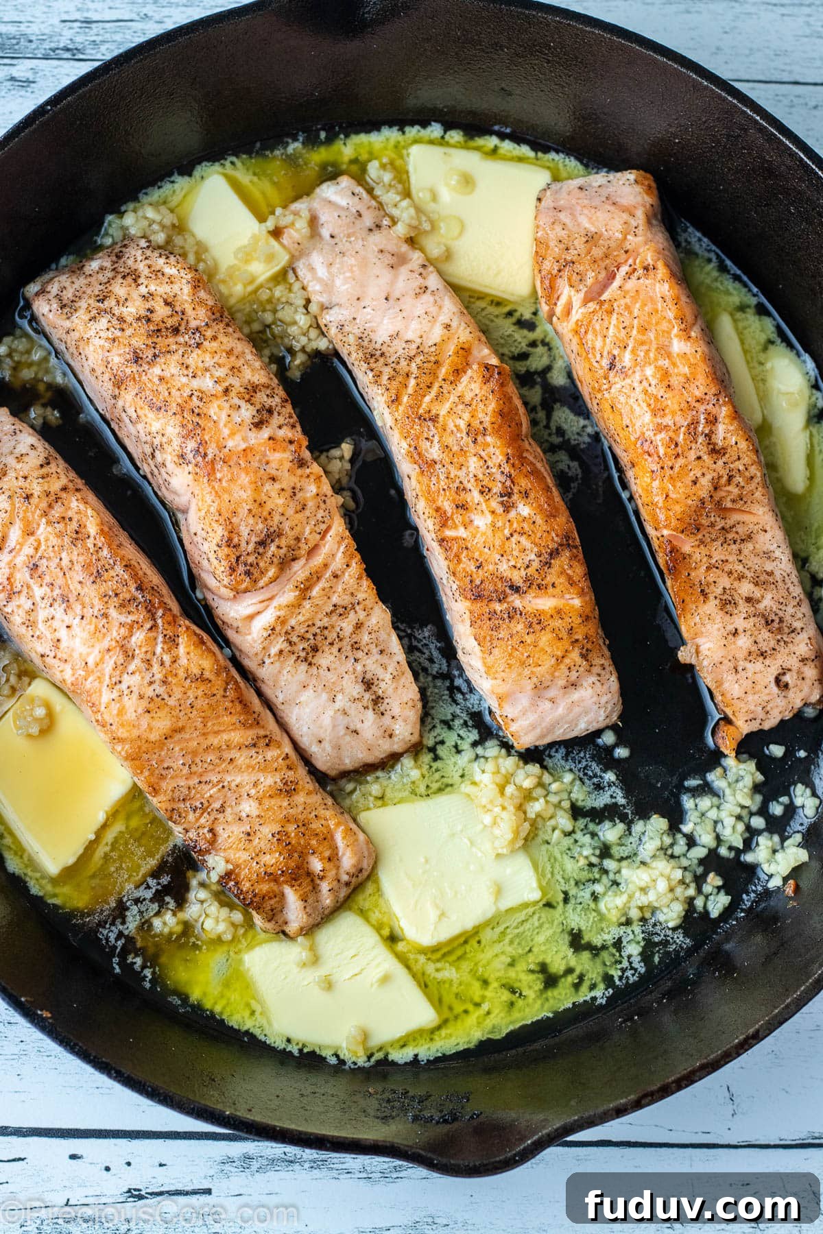 Butter and minced garlic in a cast iron skillet with seared salmon.