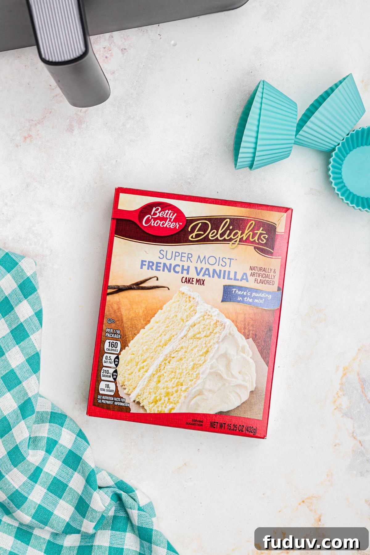 French vanilla cake mix box with empty silicone liners on a marble table.