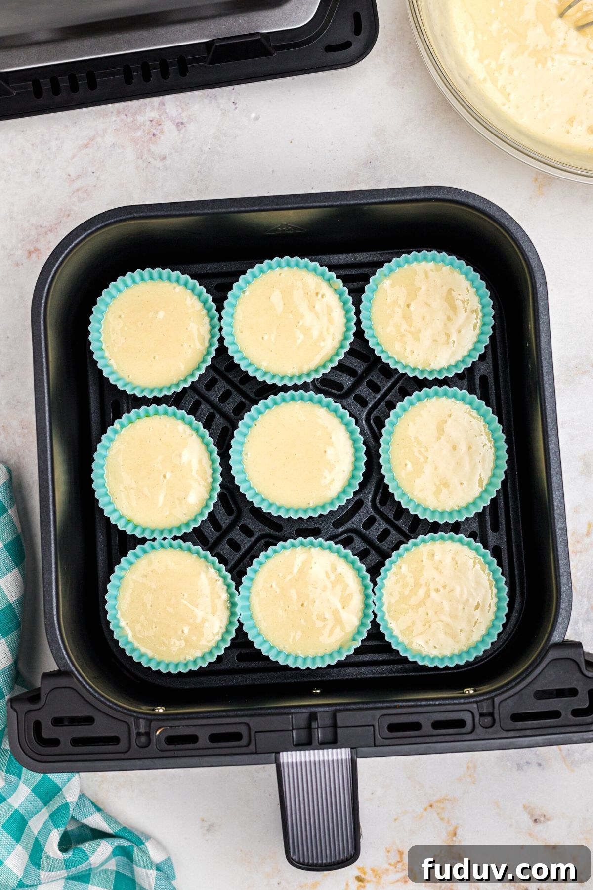 Silicone muffin liners filled with cake batter in the air fryer basket