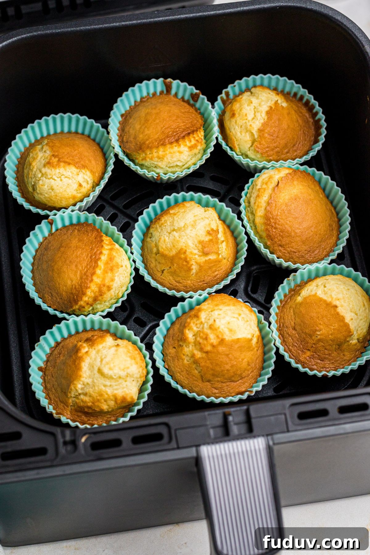 Golden French vanilla cupcakes in silicone liners in the air fryer basket.