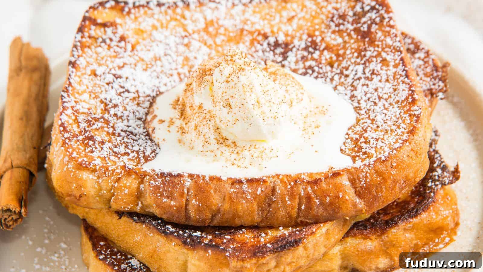 31 Cozy Cinnamon Recipes to Warm Your Home and Soul 11 Stack of French toast topped with whipped cream and powdered sugar, garnished with a sprinkle of cinnamon. A cinnamon stick rests beside it on the plate.