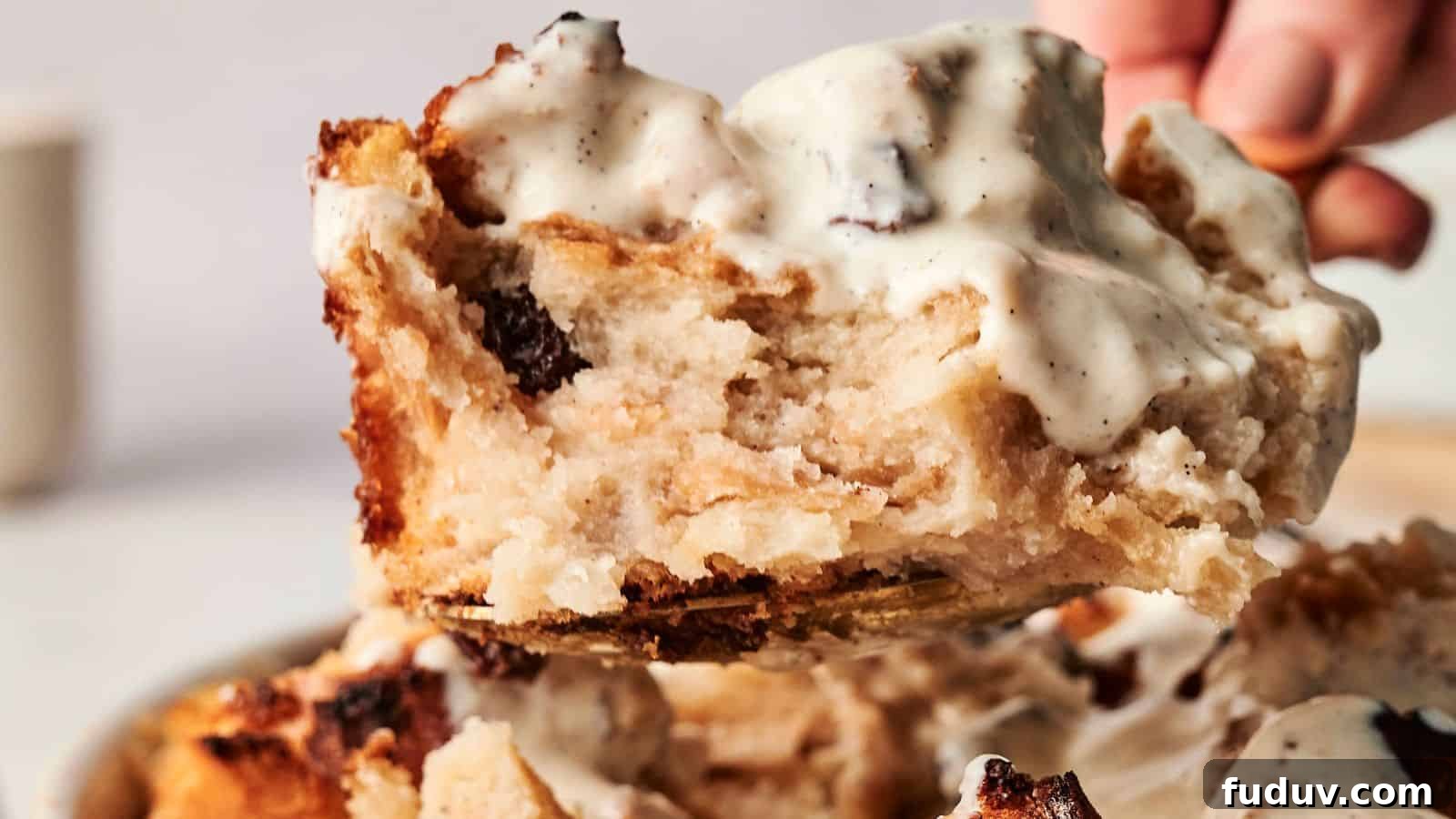 31 Cozy Cinnamon Recipes to Warm Your Home and Soul 24 A close-up of decadent bread pudding, topped with creamy vanilla sauce, is being lifted from a serving plate.