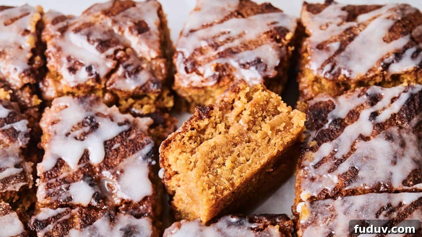 31 Cozy Cinnamon Recipes to Warm Your Home and Soul 4 Close-up of sliced crumbly cakes topped with white icing. One piece is positioned vertically to show its texture.
