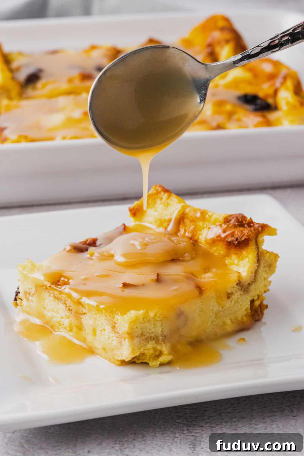 Decadent Bread Pudding with Warm Rum Sauce Recipe 2 A plate of bread pudding with rum sauce drizzled over.