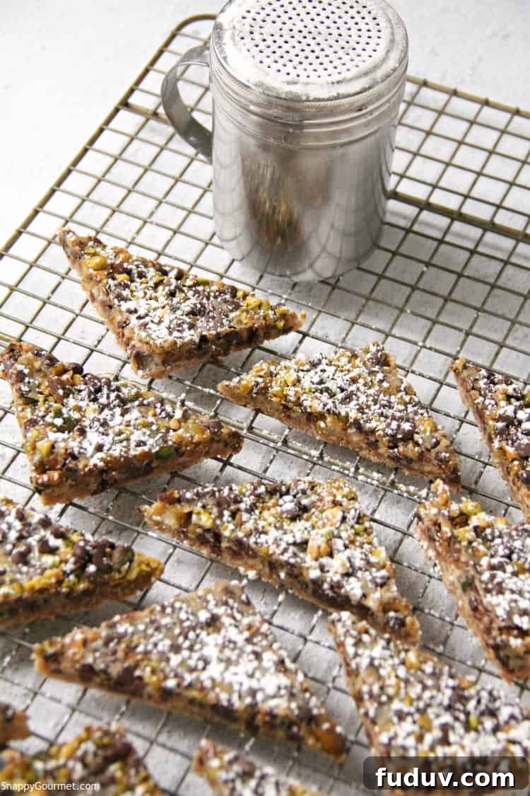 Cannoli Magic Bars - Italian inspired layered cookies with ricotta, chocolate chips, and pistachios Cannoli Magic Bars on wire rack with powdered sugar