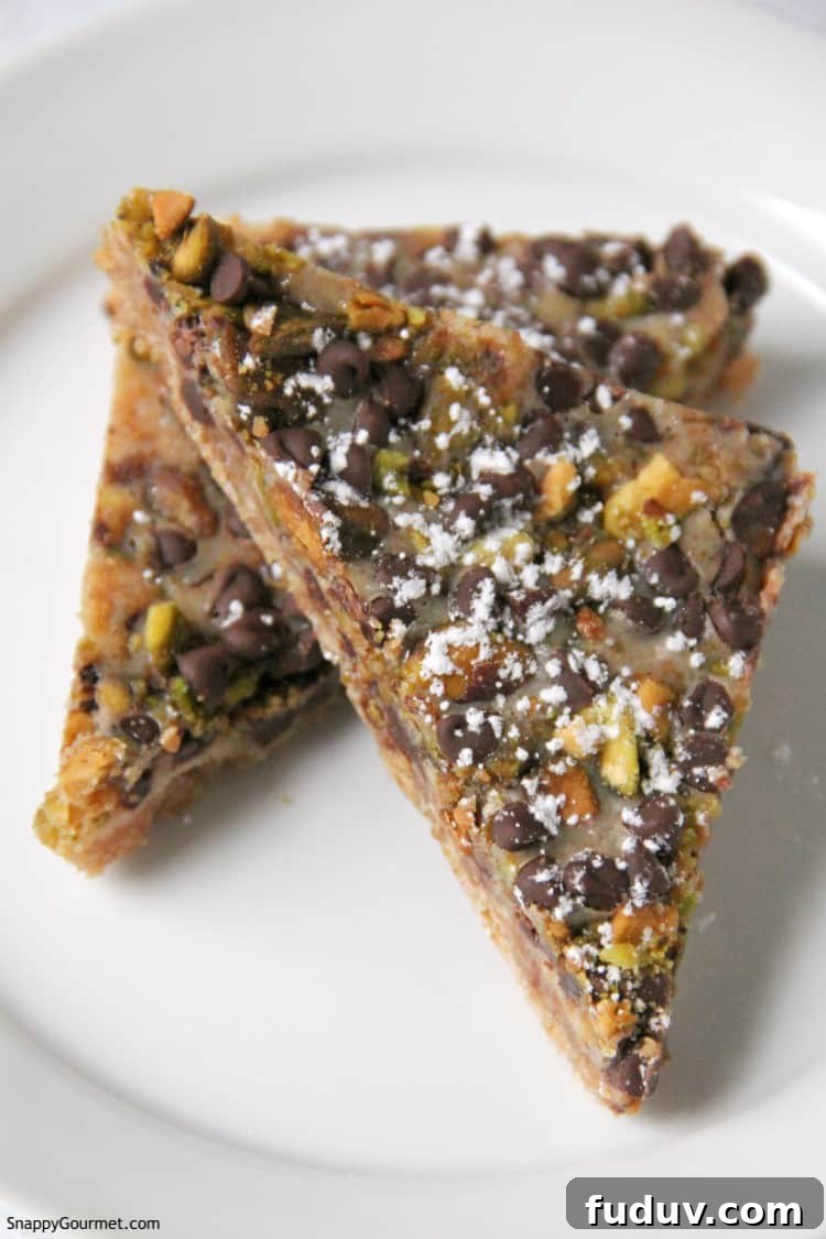 Cannoli Magic Bars recipe - Italian inspired layered dessert with ricotta, chocolate, and pistachios magic bars cut into triangle bars on white plate