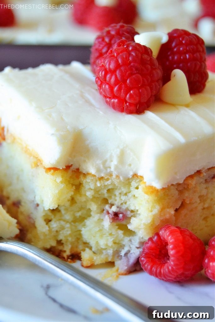 closeup of a piece of white choc raspberry cake with a bite missing