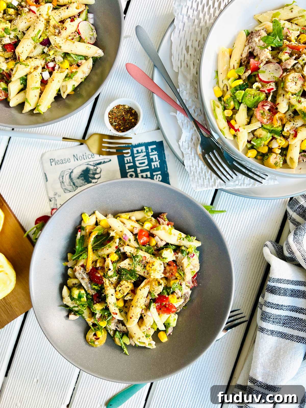 Bird's eye view of three grey plates half filled with colourful pasta penne and spanish sardines