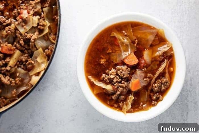 bowl of keto beef and cabbage soup next to pot of soup