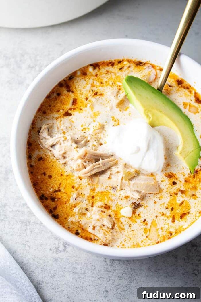 overhead view of bowl of keto white chicken chili garnished with avocado and sour cream