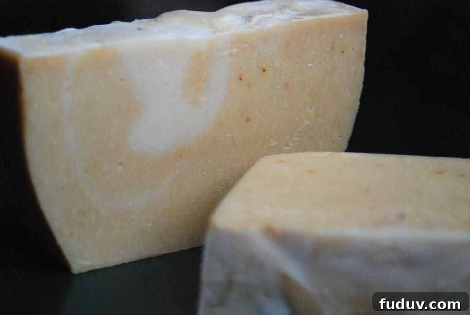 Top Essential Oil Blend Recipes for Soap Making 4 Image shows two bars of homemade orange vanilla soap, one sits on its side, and one lays on the table