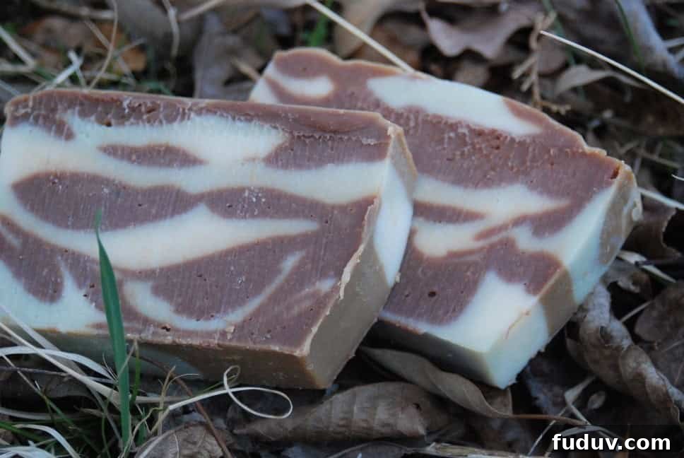 Top Essential Oil Blend Recipes for Soap Making 6 Image shows two bars of homemade soap laying in some dried leaves. The soap is marbled with white and brown to look camoflauged.