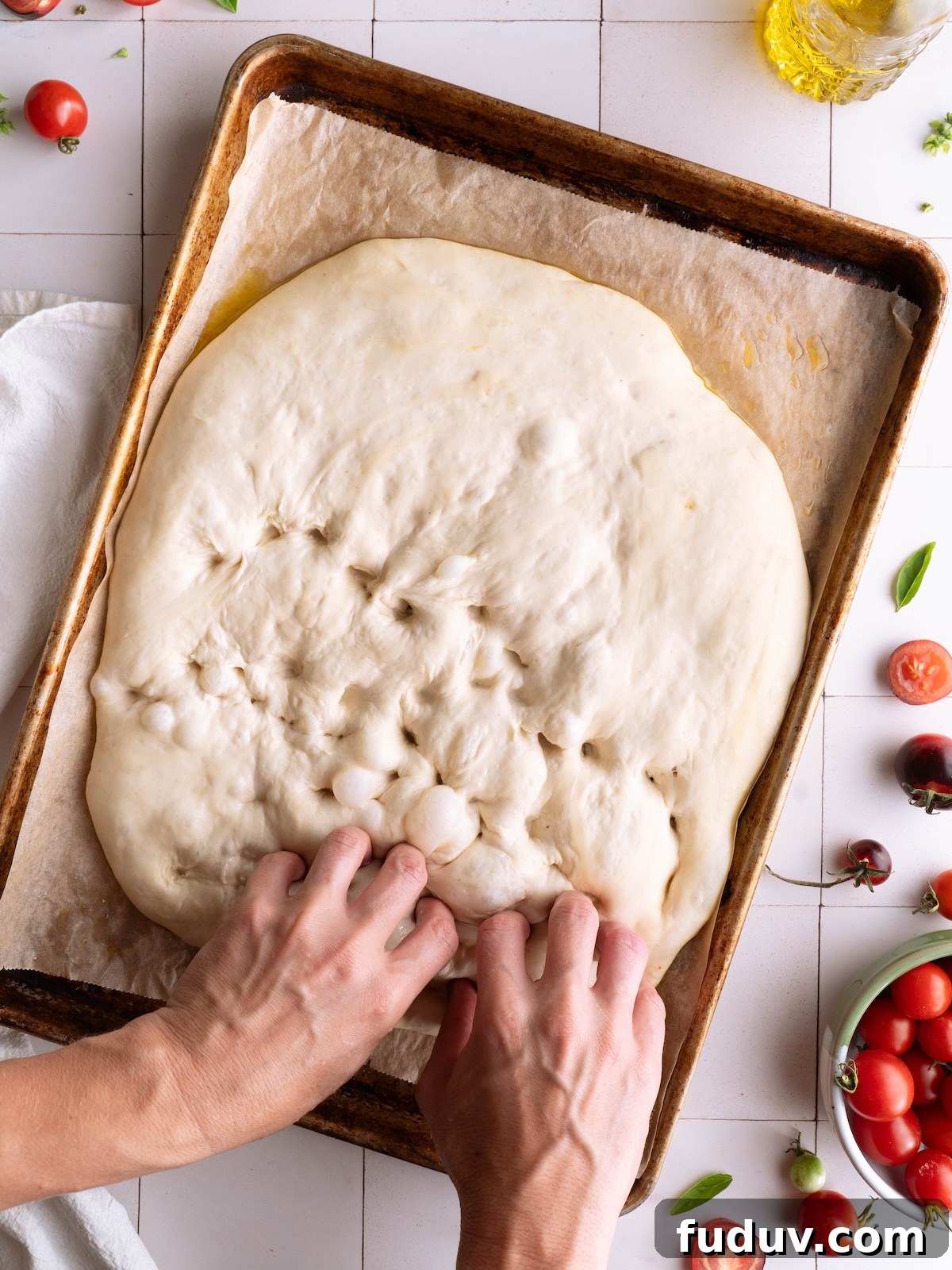 Hands dimpling homemade focaccia dough
