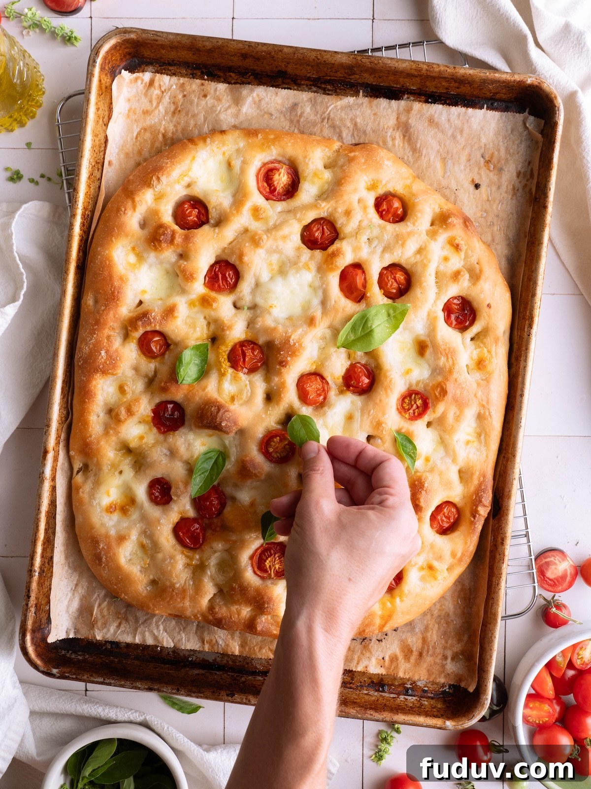 Topping fresh focaccia bread with basil leaves
