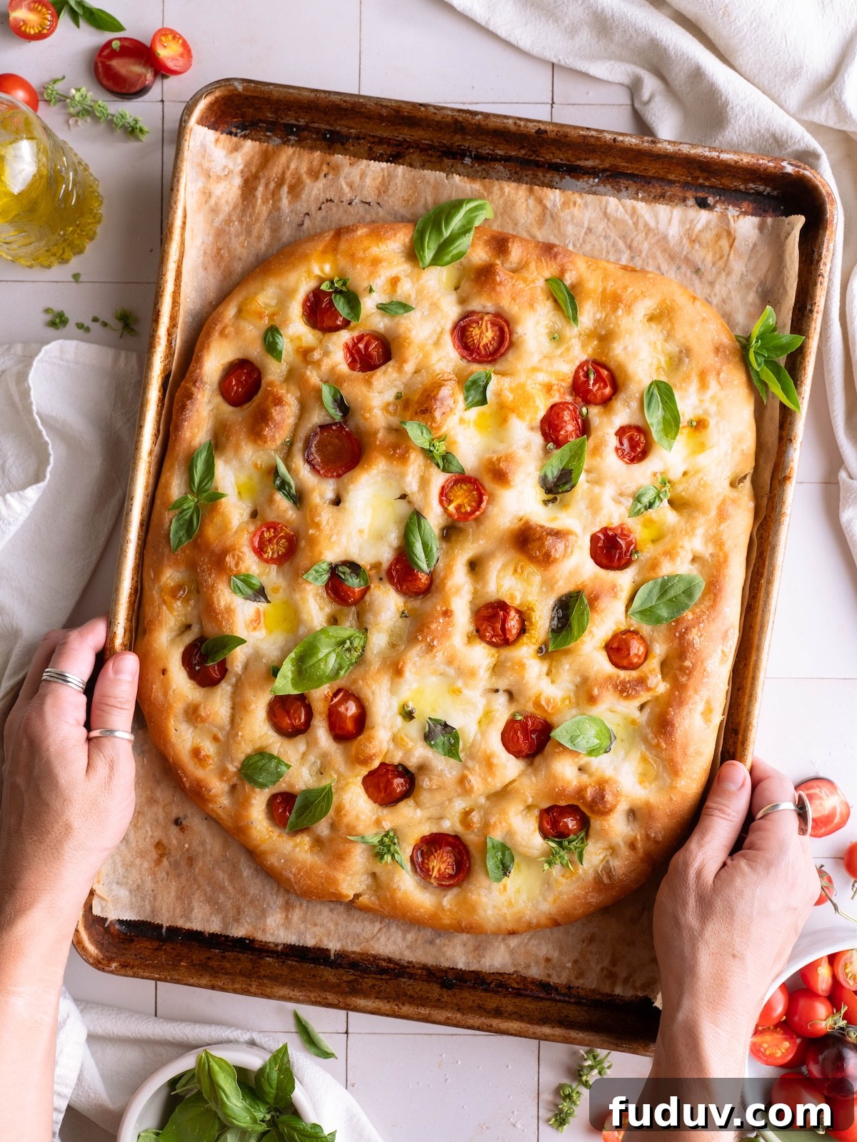 Hands holding a stunning loaf of homemade Caprese focaccia bread