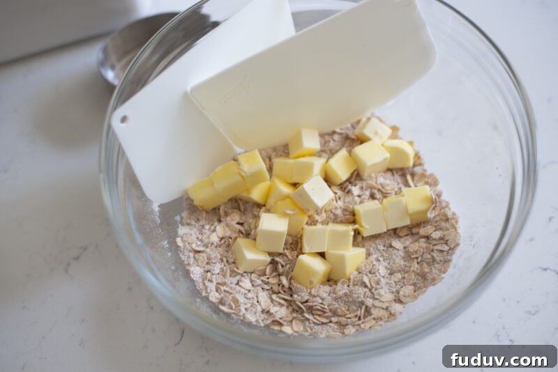Oat crisp topping is combined  in a bowl, and ready to blend with two dough scrapers.