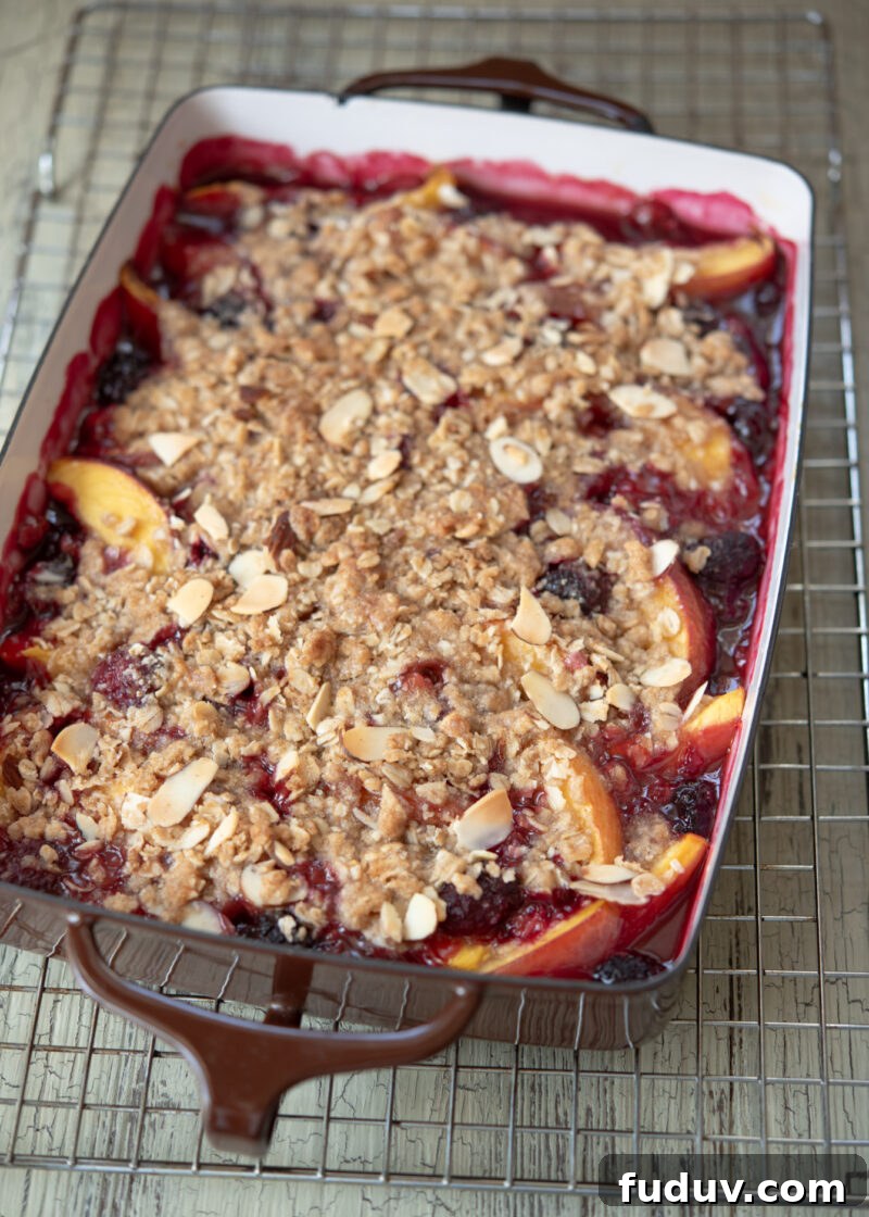 Warm nectarine blackberry crisp is cooling on a wire rack.