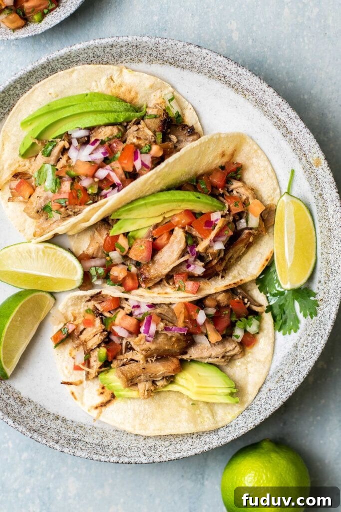 A plate of carnitas tacos with avocado.
