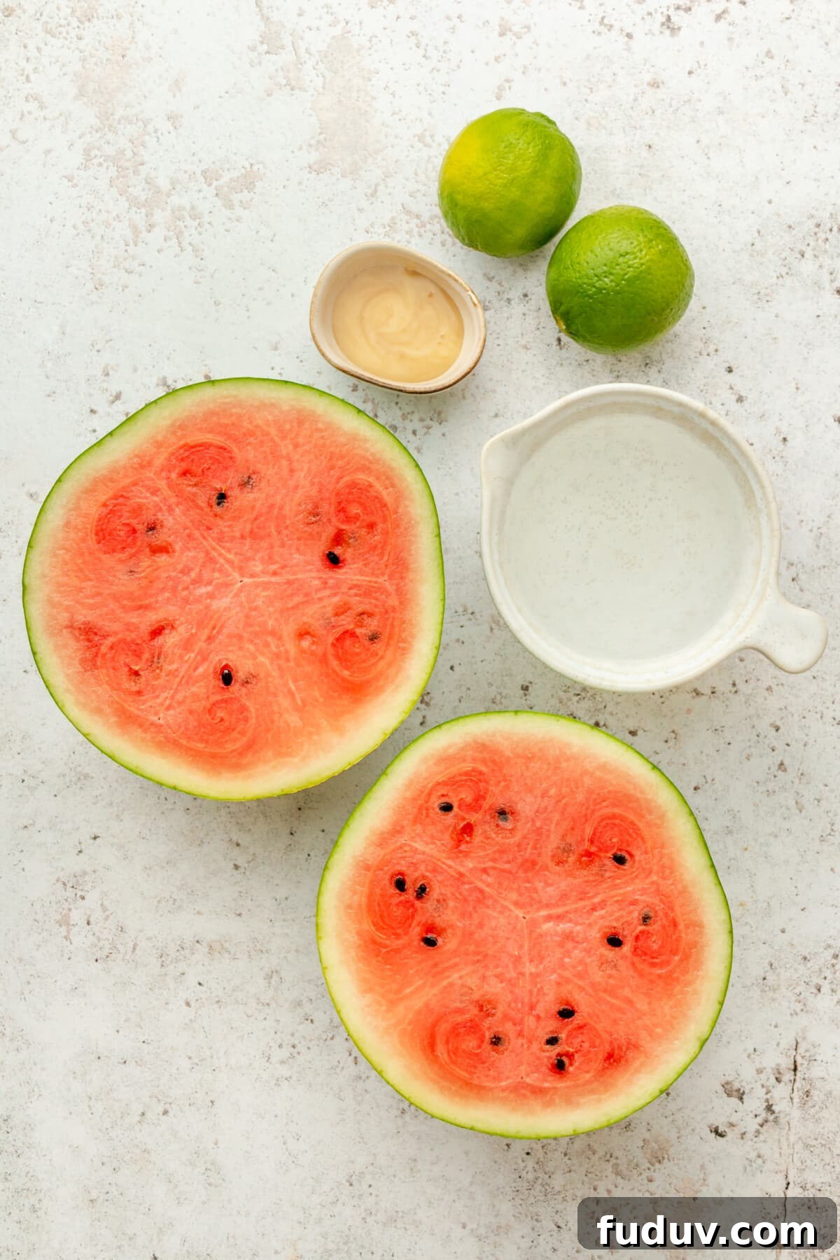 Ingredients for frozen watermelon maragaritas sit in a variety of bowls on a light grey surface.