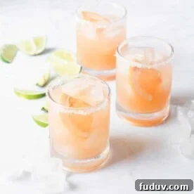 a salt rimmed glass of palomas sitting on a marble surface