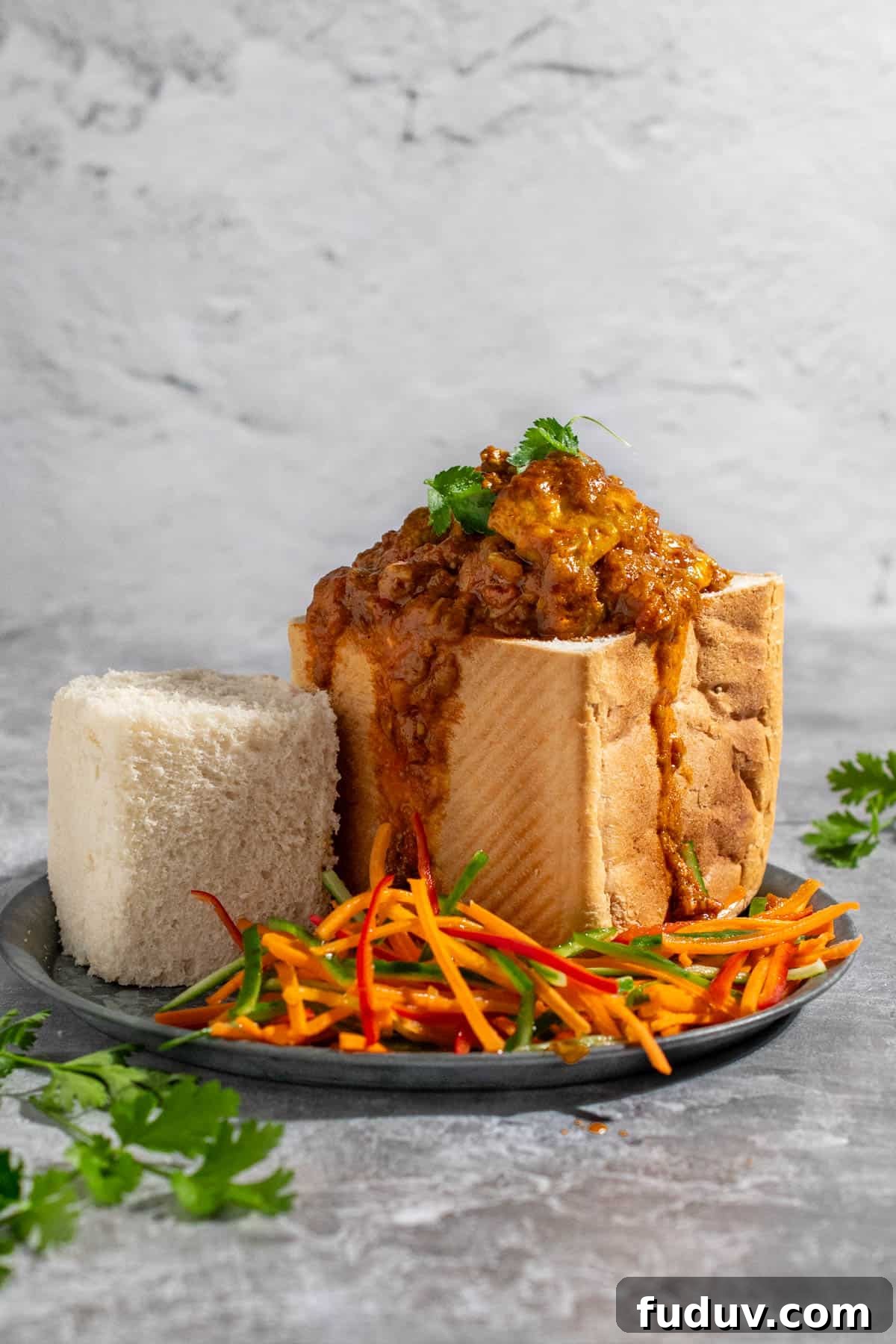 A quarter bunny chow on a plate with a carrot sambal on the side.