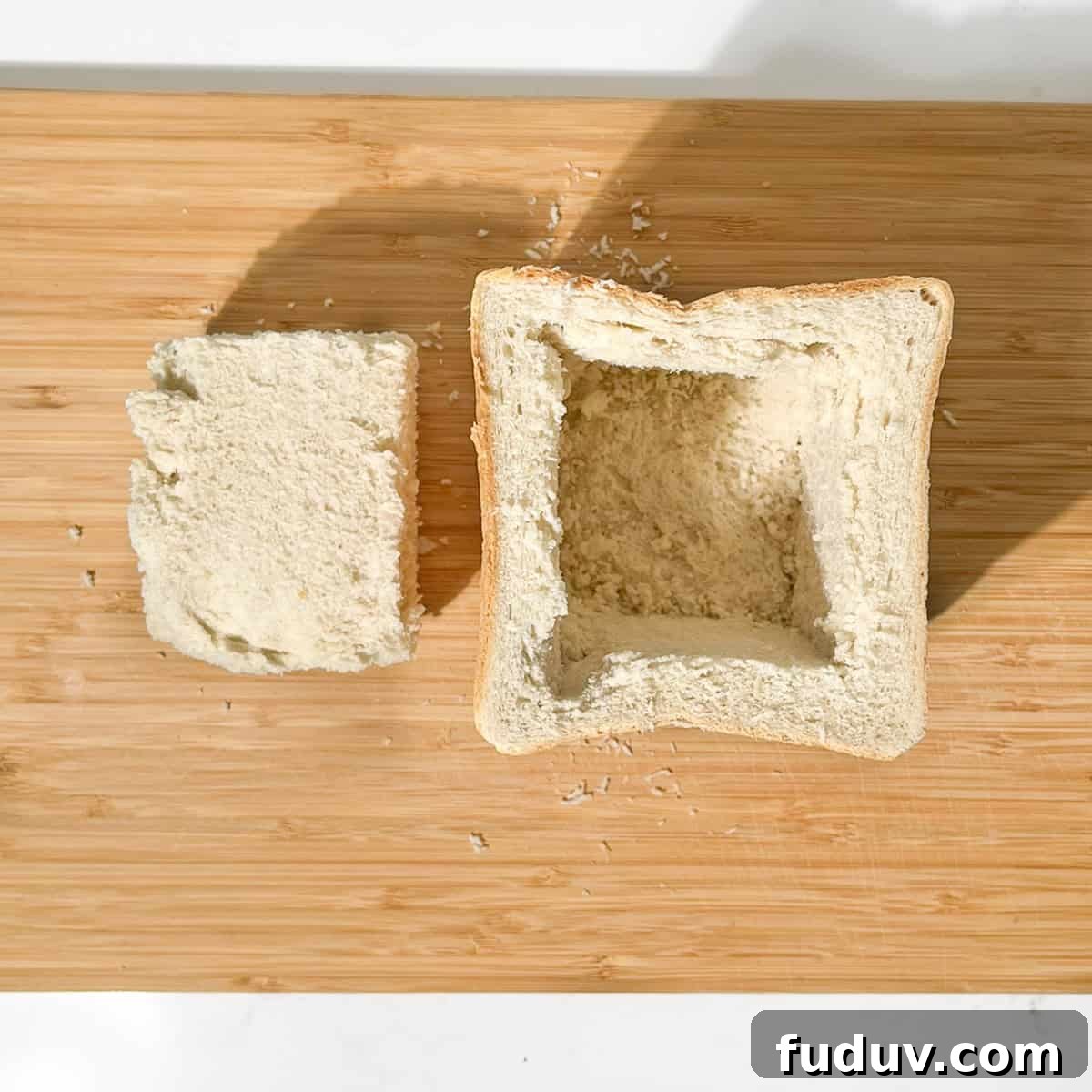 Hollowed out bread on a wooden chopping board.