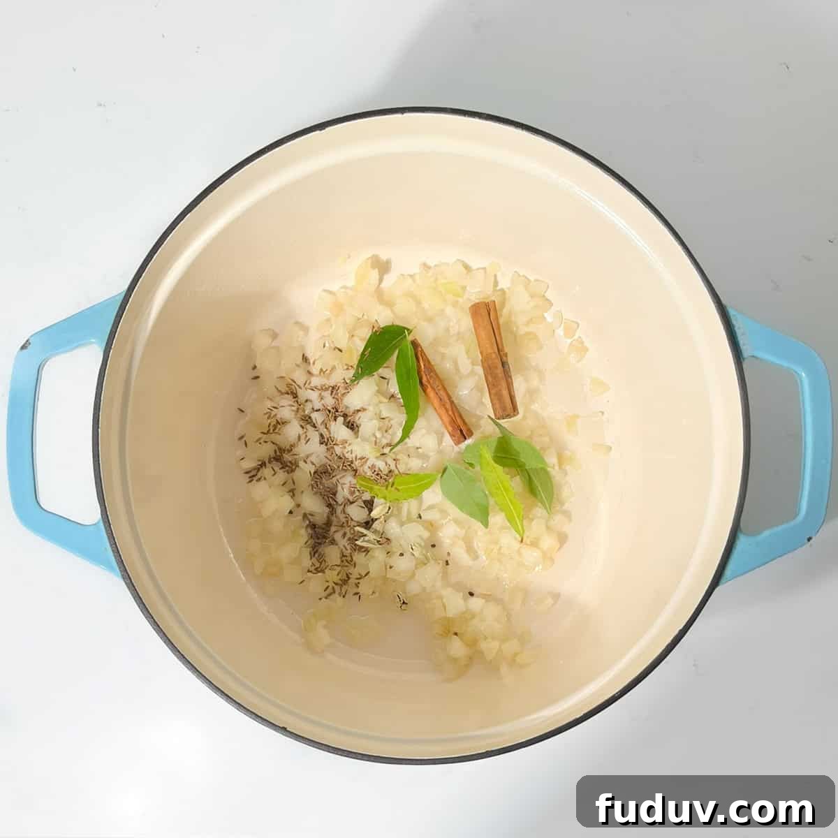 Adding onions and spices to hot oil in a large saucepan.