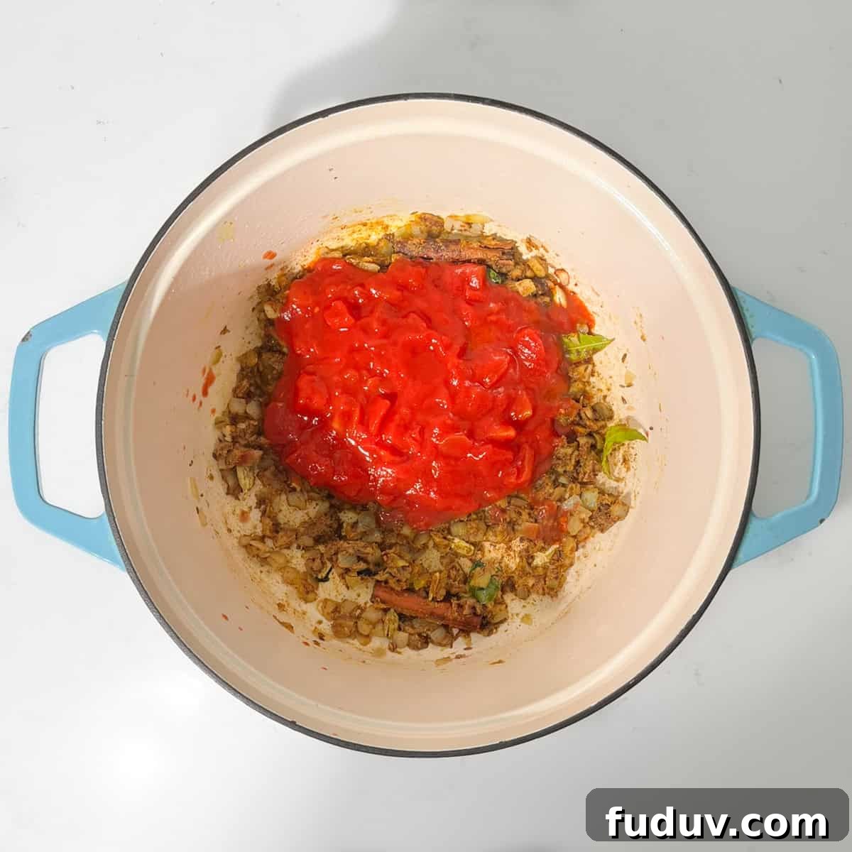 Adding chopped tomato to a saucepan for the bunny chow curry.