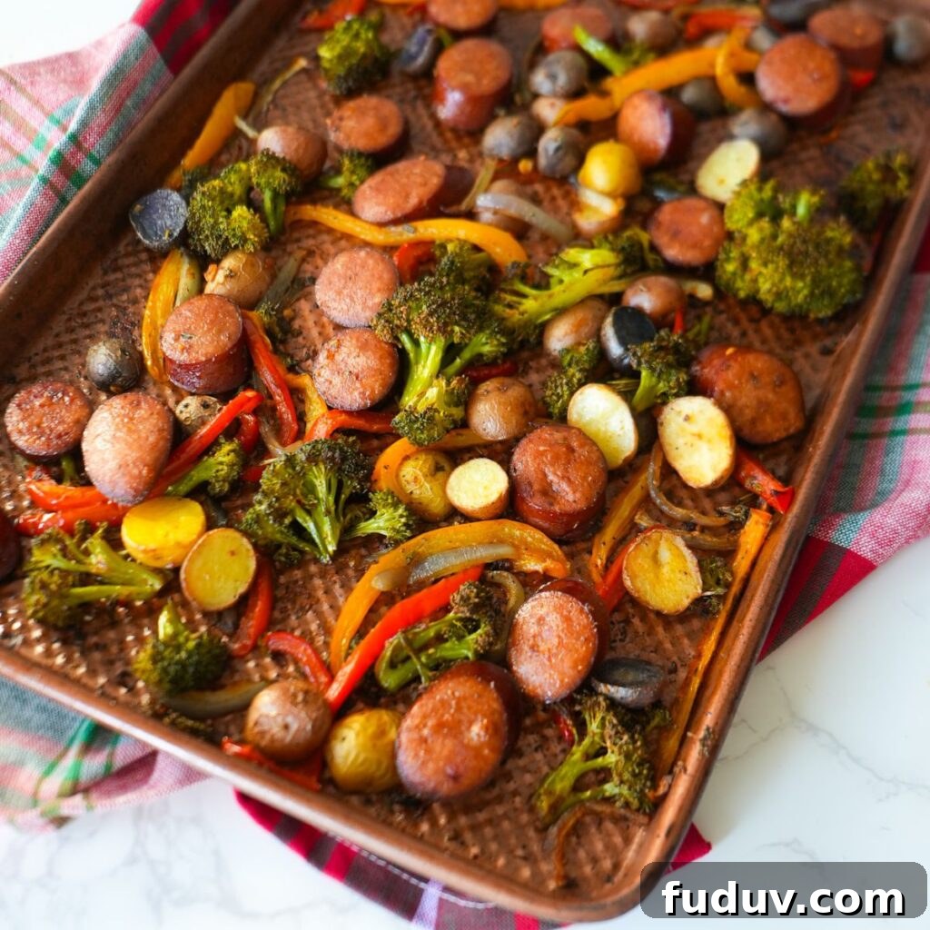Sheet pan sausage and roasted vegetables with broccoli, bell peppers, potatoes, and onions. 