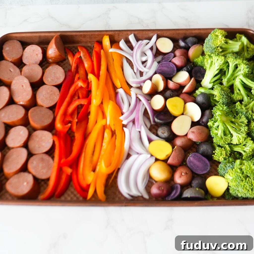 Sausage, peppers, onions, potatoes and broccoli on sheet pan.