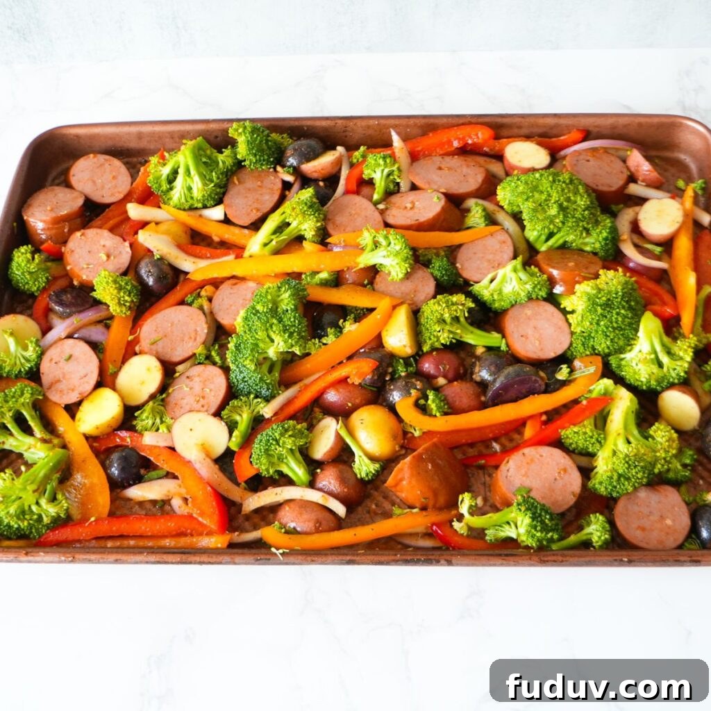 Sausage, peppers, onions, potatoes and broccoli seasoned on a sheet pan.