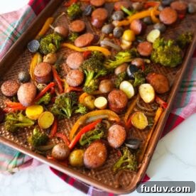 Sheet pan sausage and roasted vegetables with broccoli, bell peppers, potatoes, and onions.