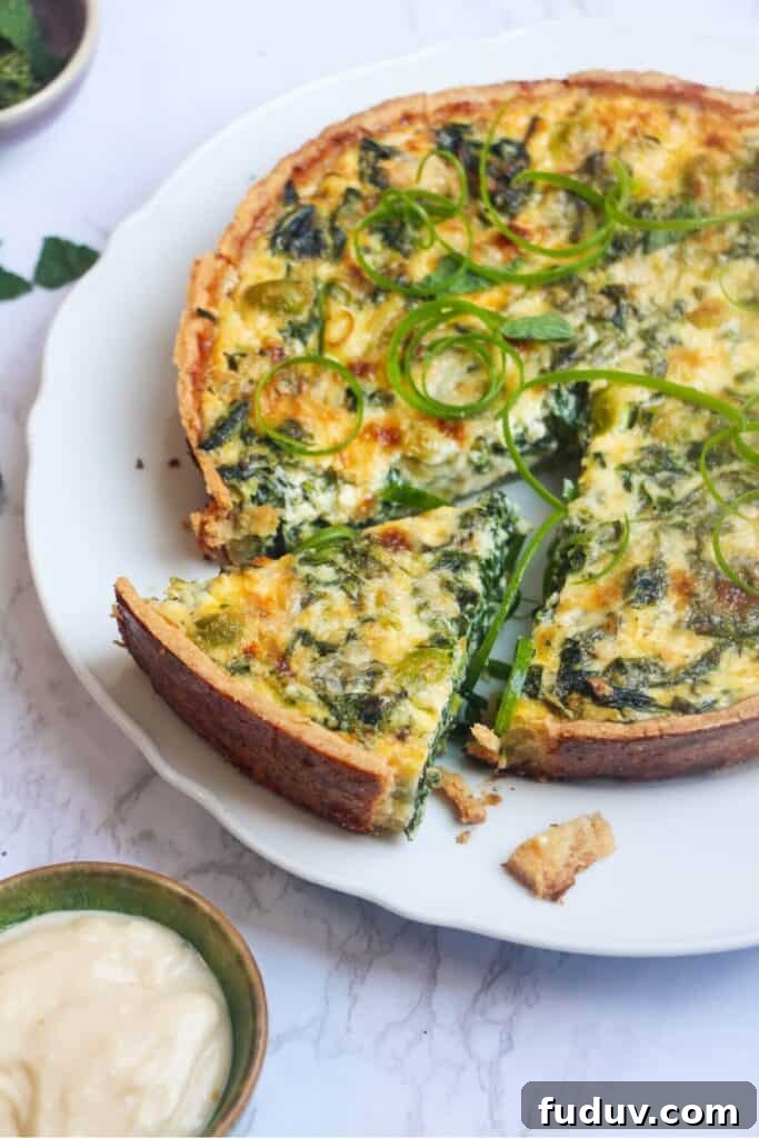 Coronation quiche on a scalloped white plate with a piece cut out of it.
