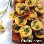 A pile of mini coronation quiches on a small wooden board.