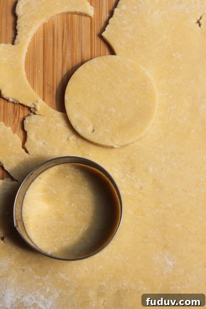 Cutting small circle of pastry out with metal cutter.