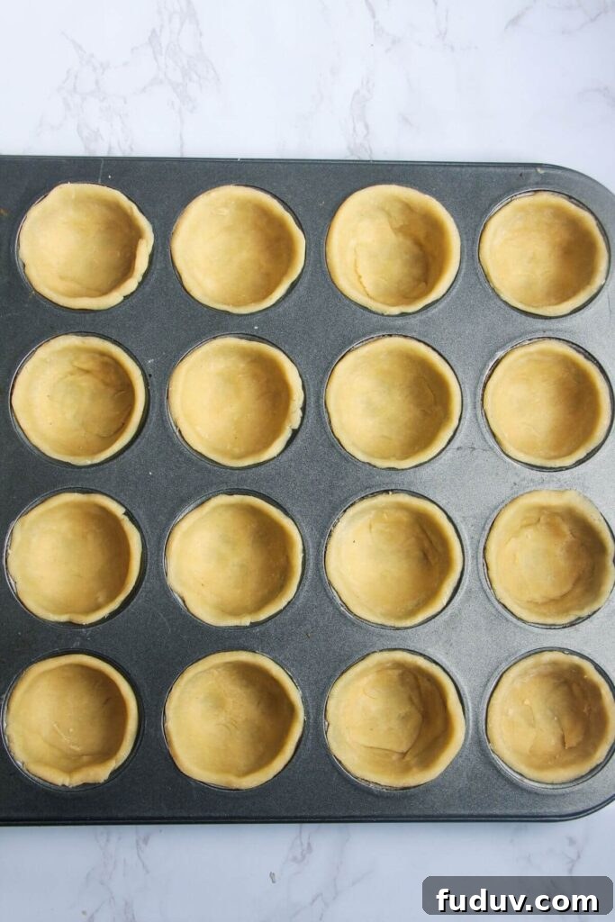 Pastry pressing into mini muffin tin.