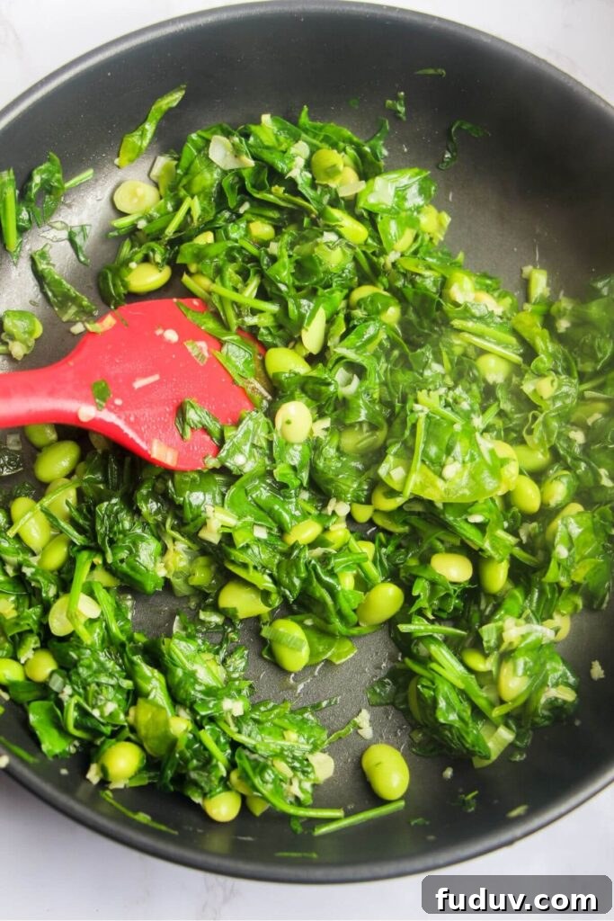 Spinach leaves wilted and cooked down in small frying pan.