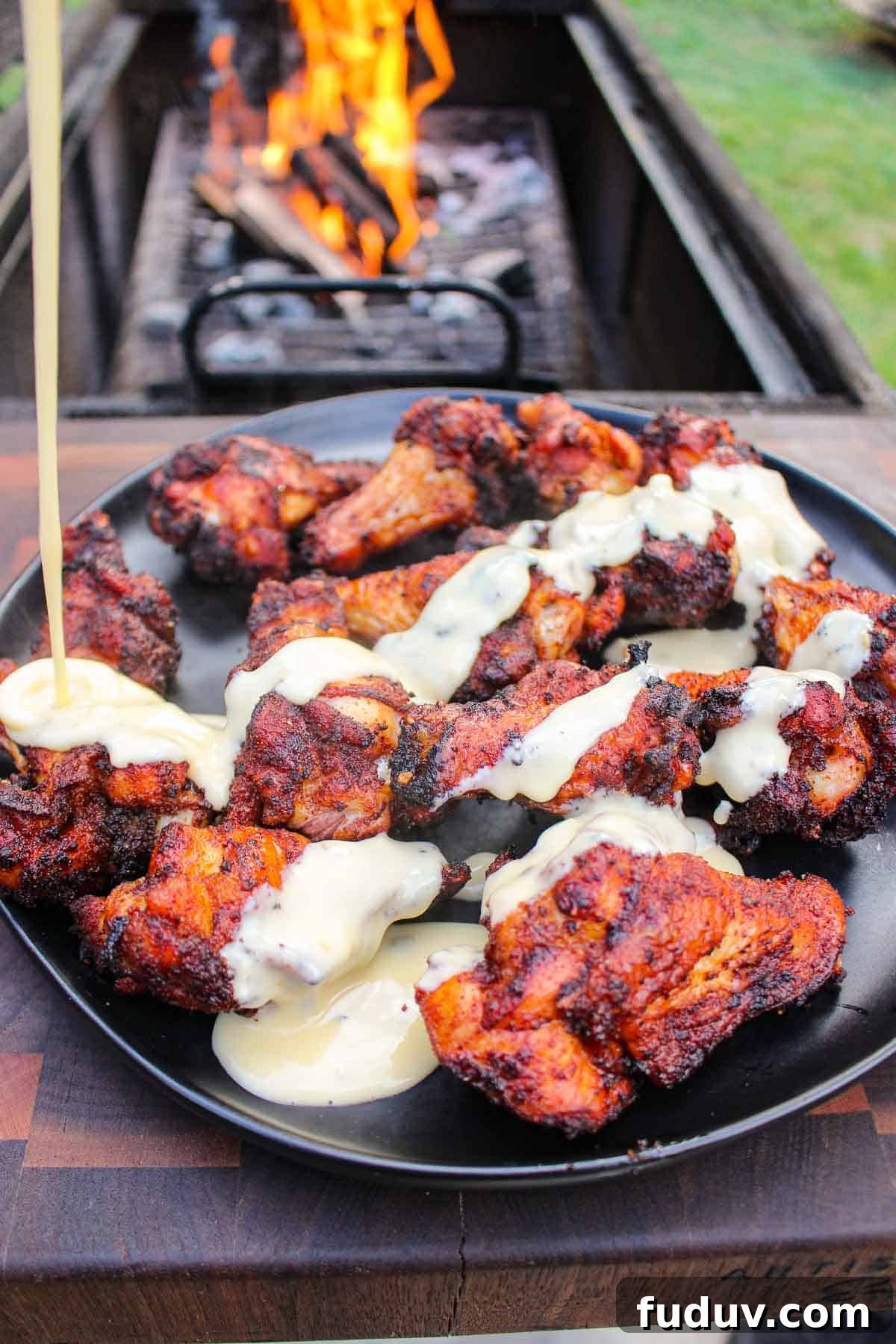 The cheese getting drizzled over the chicken wings.