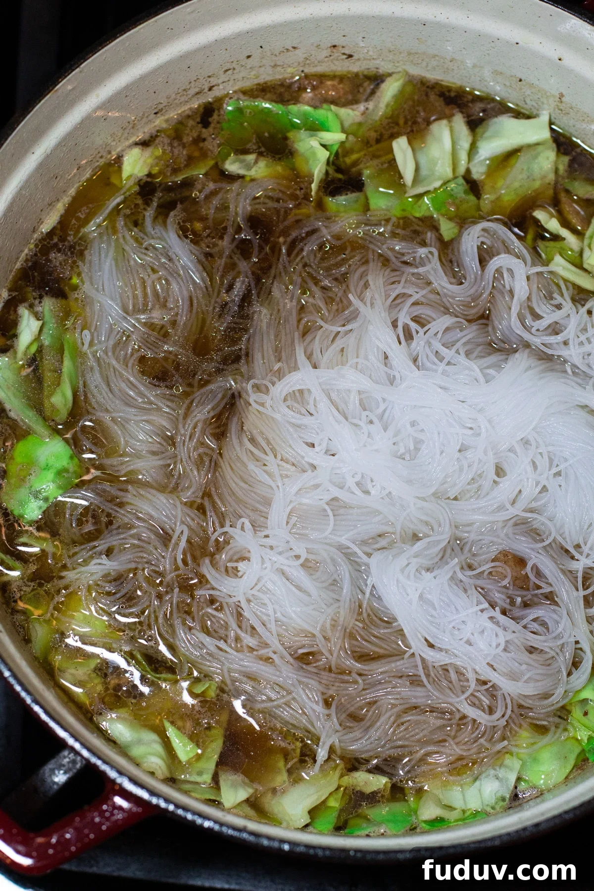 Pot of homemade chicken noodle soup with mei fun noodles and bok choy.