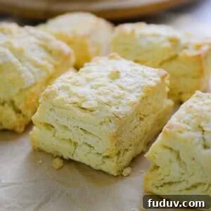 Six biscuits with self rising flour are on a piece of parchment paper all next to each other.