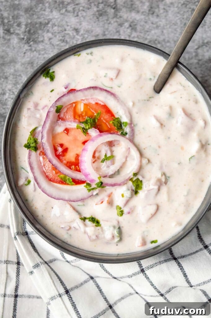 5-Minute Onion Tomato Raita Recipe for Quick Indian Sides 8 A black bowl with tomato and onion topped raita.