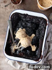 Vegan self-saucing chocolate pudding in a baking dish topped with ice cream.