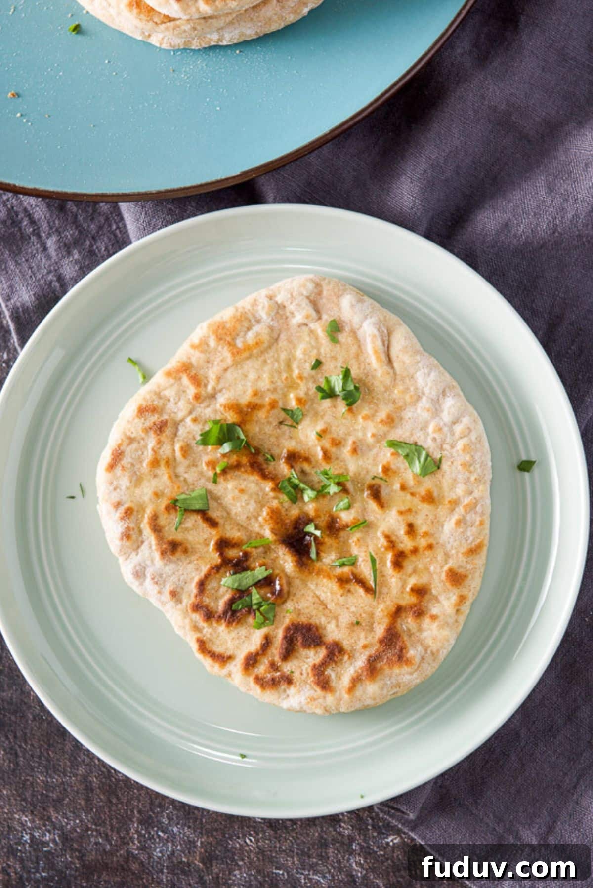 Overhead view of a piece of naan with butter and cilantro on it