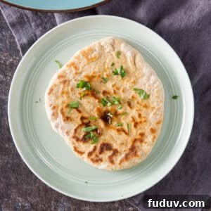 Overhead view of a piece of naan with butter and cilantro on it - square