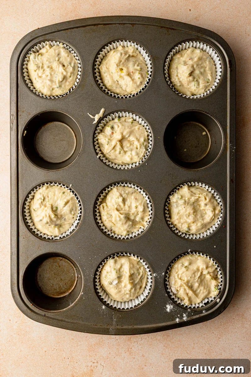 Cupcake pan with cupcakes liners and unbaked pistachio cupcakes batter.