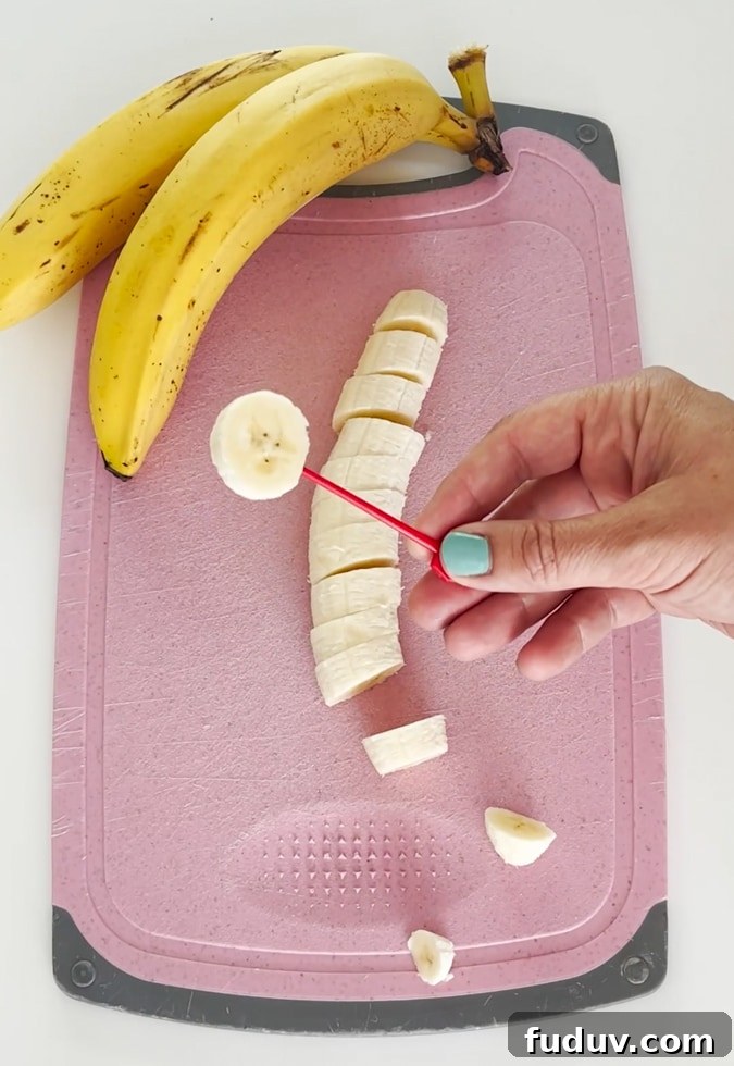 Small plastic food skewer being inserted into the banana slice.