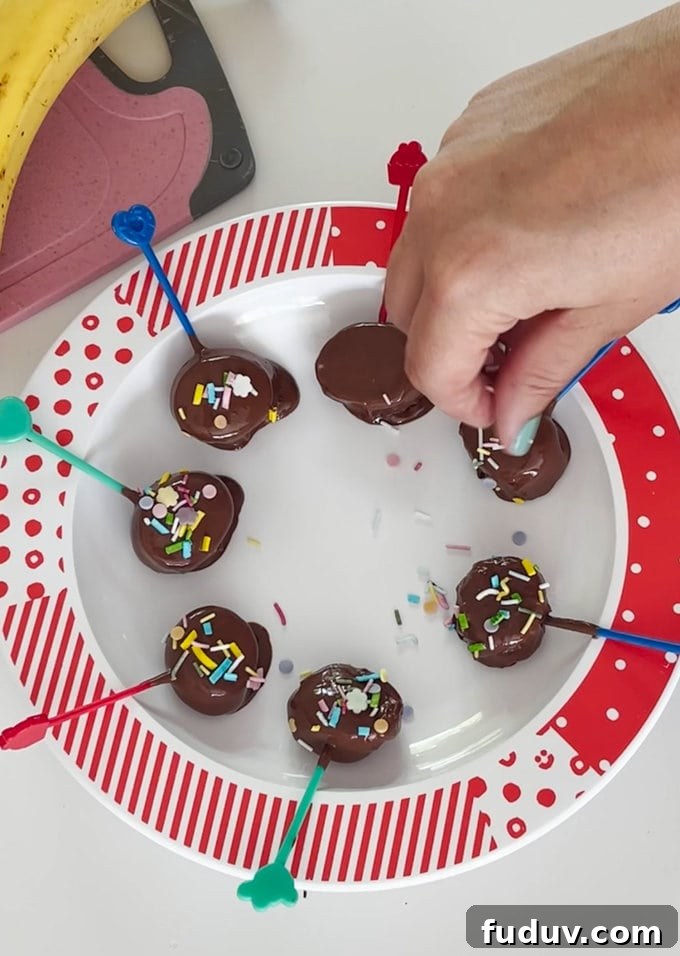 Banana slices laid out in a circle on a plate and coloured sprinkles are being added.